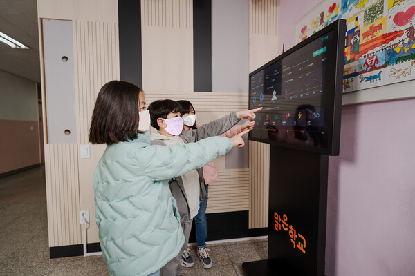 공기질 모니터링 시스템으로 실내 공기청정도를 확인하고 있는 보라매초등학교 학생들. /사진=한화그룹