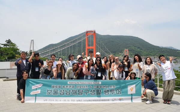 농촌크리에이투어 프로그램의 일환으로 열린 '보물섬 남해 탐구생활 팸투어'에 참여한 글로벌 농촌관광 서포터즈 및 인플루언서들이 남해대교를 배경으로 기념촬영을 하고 있다. 남해군 제공