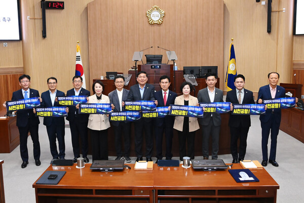 사천시의회 의원들이 제286회 임시회 본회의에서 ‘사천공항 국제공항 승격 촉구’ 문구가 적힌 현수막을 들고 기념촬영을 하고 있다. 사천시의회 제공