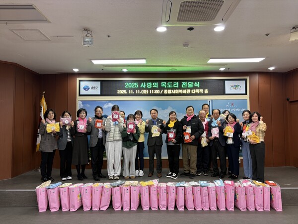 남해군 관계자와 자원봉사자들이 ‘2025 사랑의 목도리 전달식’에서 완성된 목도리를 들고 기념촬영을 하고 있다. 남해군 제공