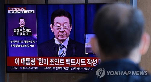이재명 대통령이 14일 팩트시트 확정 사실을 발표하는 영상을 한 시민이 시청하고 있다. 연합뉴스